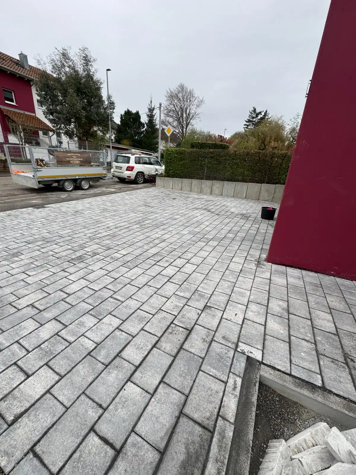 Nachher-Ansicht der fertig gestellten Einfahrt von Molle GaLaBau: Fachgerecht erstellter Unterbau, komplett neu verlegtes, graues Pflaster und eine ebene, großzügige Nutzfläche.