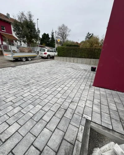 Nachher-Ansicht der fertig gestellten Einfahrt von Molle GaLaBau: Fachgerecht erstellter Unterbau, komplett neu verlegtes, graues Pflaster und eine ebene, großzügige Nutzfläche.